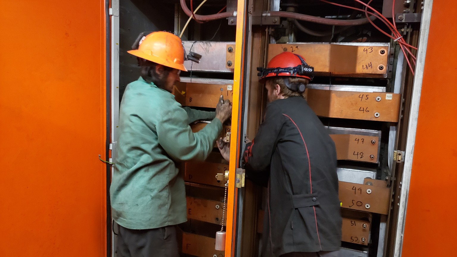 Two workers performing elevated repair work inside an industrial building