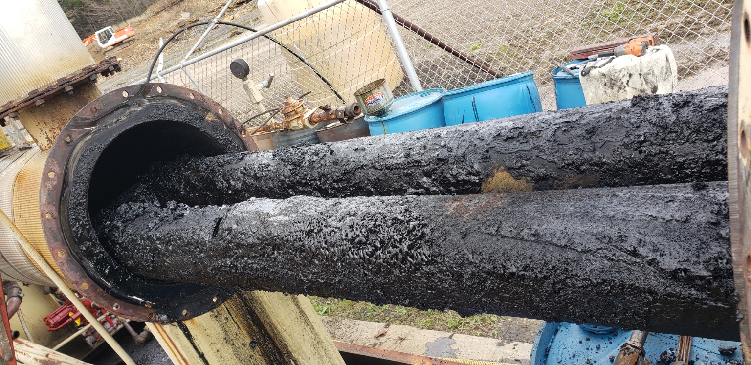 Black fouled process pipes being pulled from equipment