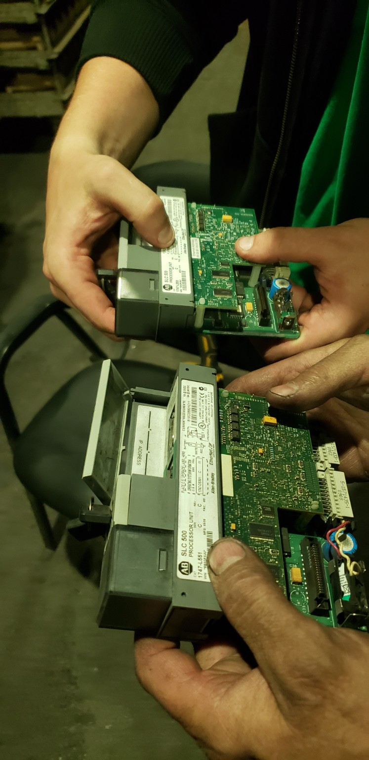 Technicians holding PLC modules during controls work